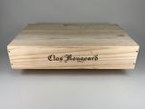 La boîte est en bois et porte un nom gravé dessus.