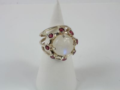 un gros plan d'une bague ornée d'une pierre blanche entourée de pierres rouges