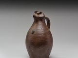 un vieux vase marron posé sur une table blanche