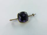 a close up of a purple stone on a gold plated pin