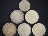 six different british coins on a black background