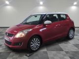 Une Suzuki Swift rouge est garée sur un sol à damier.