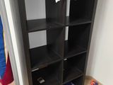 une bibliothèque noire surmontée d'un tas de livres