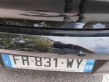 a reflection of a person standing in the reflection of a car ' s license plate