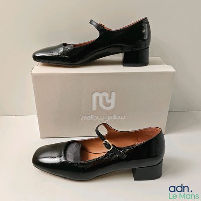 the woman ' s black shoes are sitting on top of a box