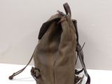brown leather backpack on white surface with white wall in background
