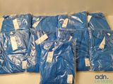 plusieurs sacs remplis de chemises bleues posés sur une table blanche