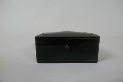 une petite boîte noire posée sur une surface blanche