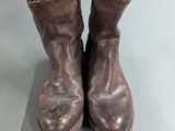 pair of brown leather boots sitting on top of a gray surface