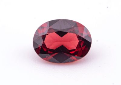 un gros plan d'une pierre de grenat rouge sur une surface blanche