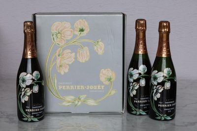three bottles of champagne sitting next to a box on a table