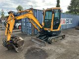 an image of a small excavator parked in front of a shipping container