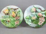 two plates with fruit and flowers painted on them sitting on a table