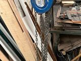 a blue crane hanging from a chain next to a pile of wood