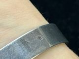a close up of a person ' s wrist wearing a silver bracelet