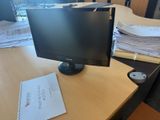 a computer monitor sitting on a desk next to a pile of papers