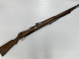 un fusil avec un canon en bois sur une surface blanche