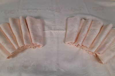 several folded napkins on a white table cloth with a white background