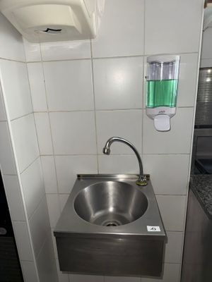 a stainless steel sink in the corner of a public restroom