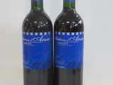 two bottles of red wine sitting next to each other on a table