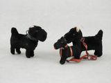 deux petits chiens noirs tenus en laisse dans la neige