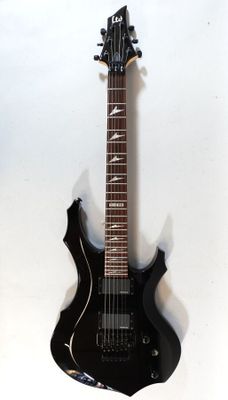 a black electric guitar hanging on a wall