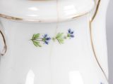 a white pitcher with blue flowers on it on a table