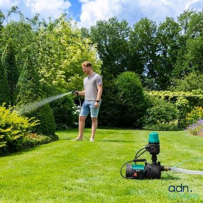 the man is watering the grass in the yard with a hose