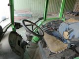 volant d'un tracteur vert avec un sac posé sur le siège