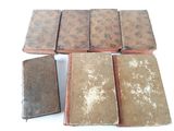 several old books sitting on top of each other on a white surface