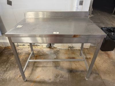 an image of a stainless steel work table with a trash can in the background