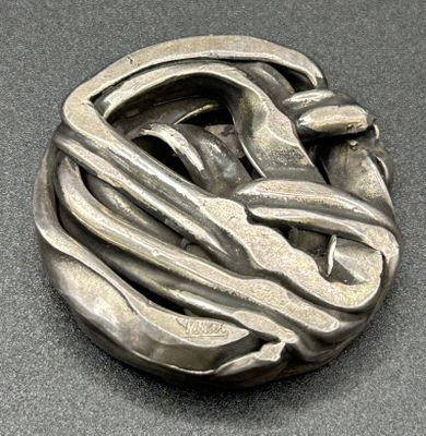 a silver brooch with a design on it on a table