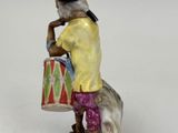 a figurine of a man with a drum on a rock