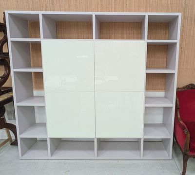 une bibliothèque blanche devant laquelle se trouve une chaise rouge
