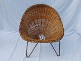 a wicker chair on a metal stand against a white backdrop