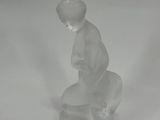 a small glass figurine of a boy sitting on a rock