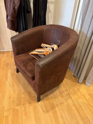 a brown chair with a book on it in front of a window