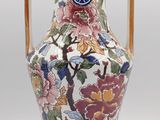 a vase with a handle that has flowers on it