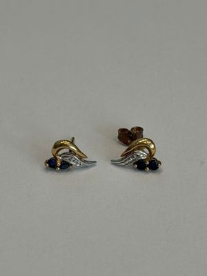 une paire de boucles d'oreilles en or et en argent posées sur une surface blanche