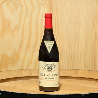 a bottle of wine sitting on top of a wooden barrel
