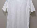white t - shirt hanging on a hanger against a wall