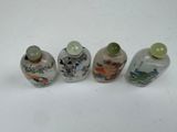 three small glass bottles with designs on them sitting on a white surface