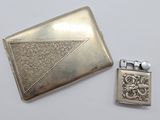 un étui à cigarettes ancien en argent et un briquet posés l'un à côté de l'autre