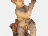 une photo représentant la statue d'un enfant assis sur une souche d'arbre