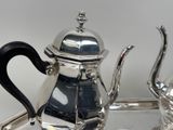 a silver tea pot sitting on a tray on a table