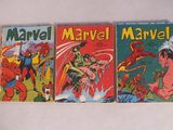 Trois bandes dessinées Marvel anciennes sont exposées sur un support blanc