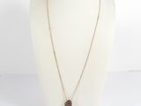 un collier en or avec un pendentif en pierre marron sur un mannequin blanc