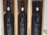 three bottles of wine in a wooden box on a table