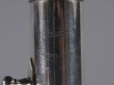 an antique silver plated musical instrument with a flute in the foreground