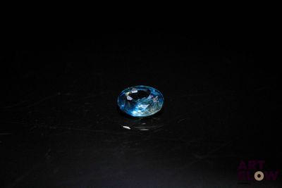 a close up of a blue diamond on a black surface